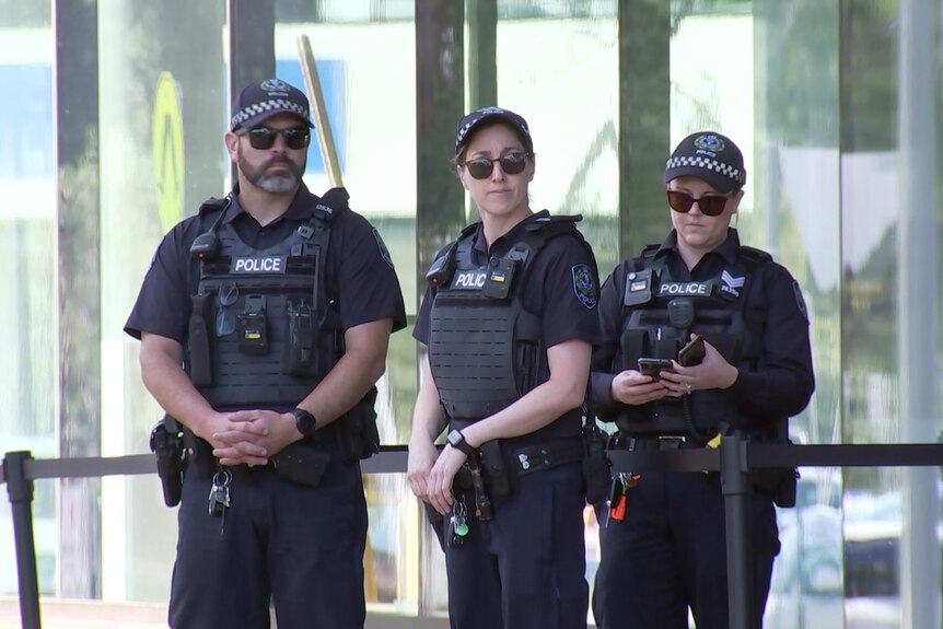 Three police officers stand outside a building