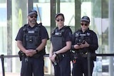 Three police officers stand outside a building