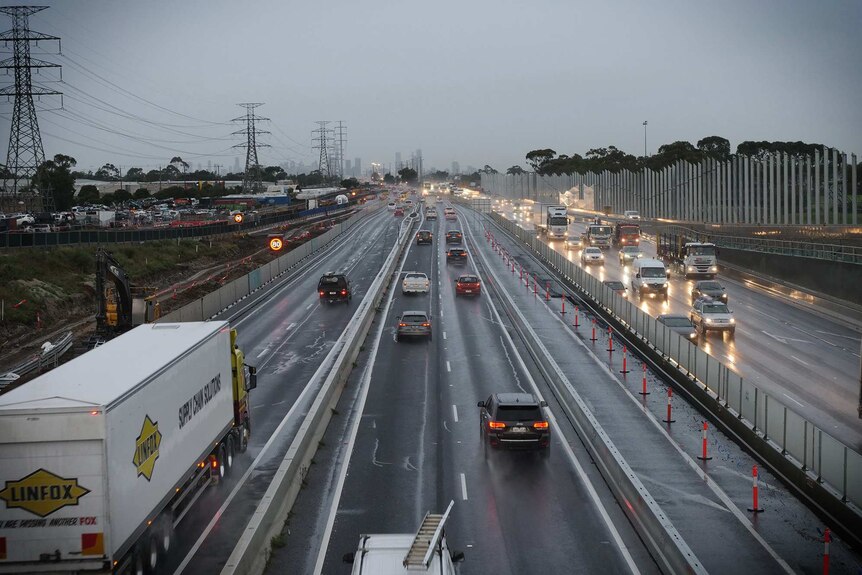 The view from an overpass shows medium-level traffic heading towards the Melbourne CBD on a rainy morning