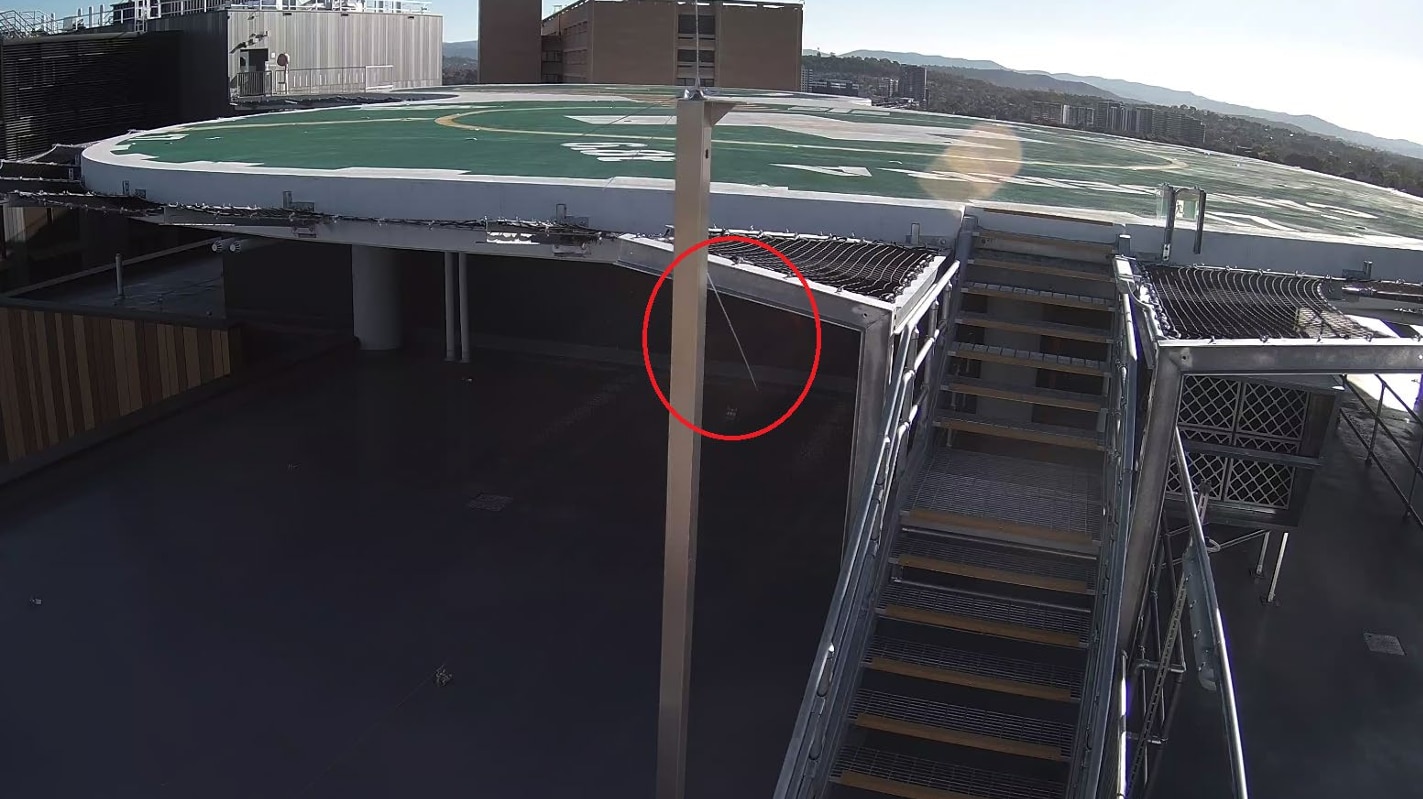A photo of a helipad where an antenna is visibly suspended in the air with a red circle drawn around it.
