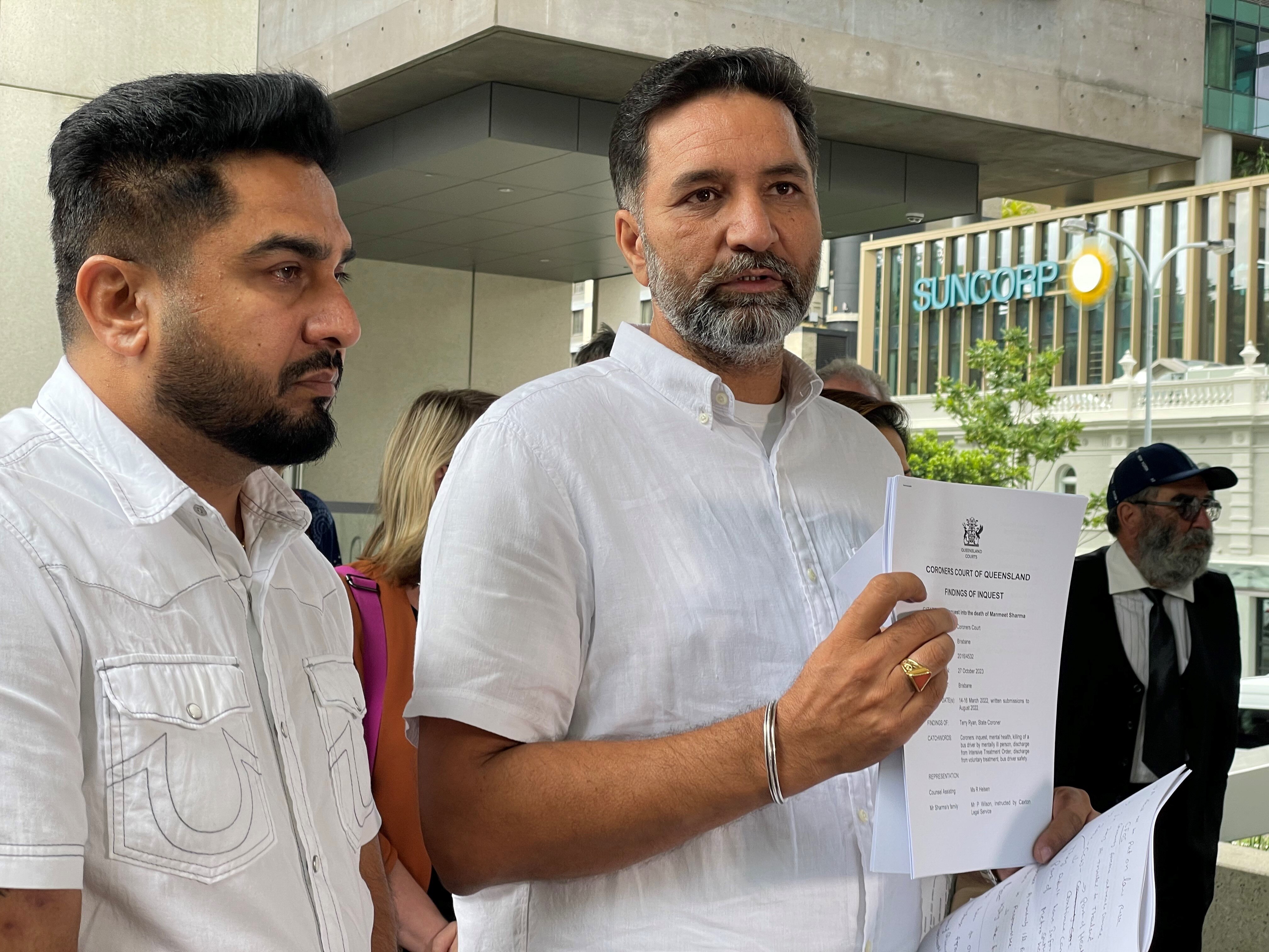 two men stand out the front of a Brisbane court holding documents from the inquest