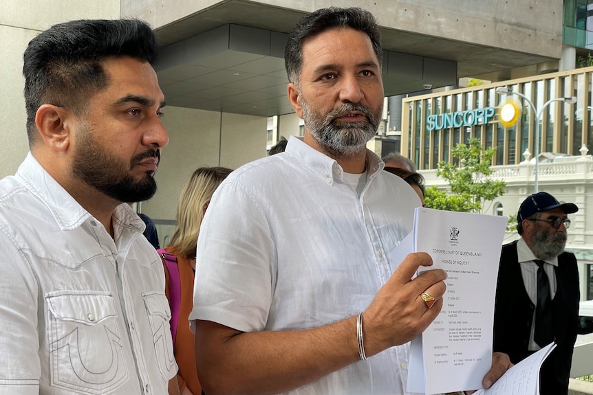 two men stand out the front of a Brisbane court holding documents from the inquest