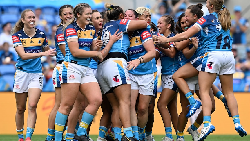 A women's rugby league team celebrate a victory 