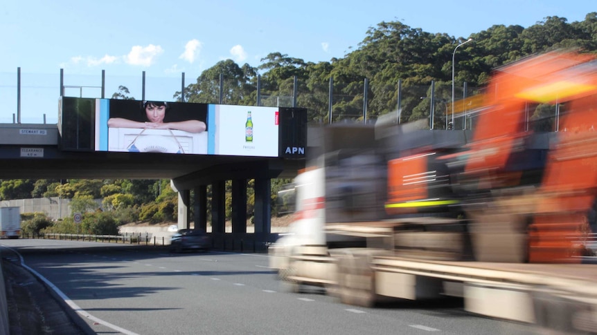 A truck passes under a large electronic billboard on the M1 at Tugun.