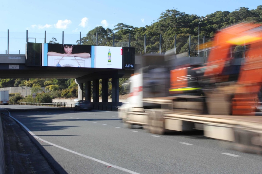 A truck passes under a large electronic billboard on the M1 at Tugun.