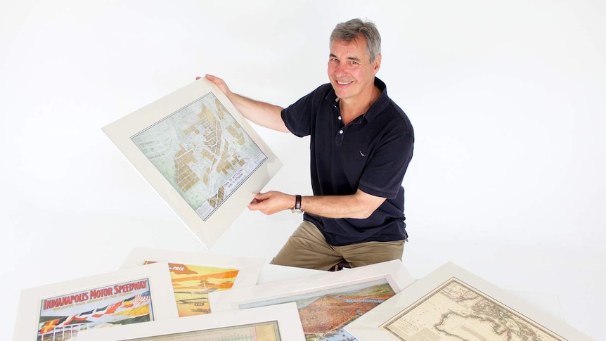 Tony Sheffield sits in his photography studio with some of his restored maps.