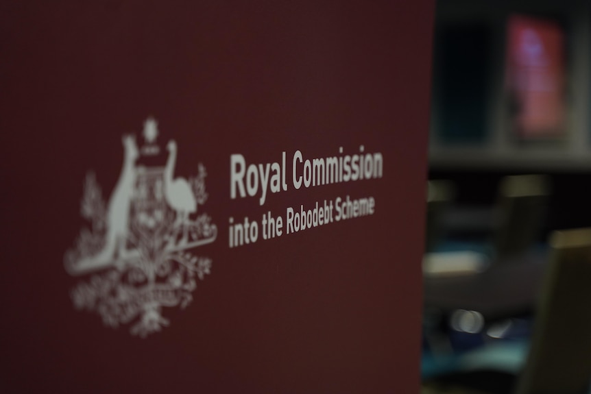 Robodebt royal commission sign on maroon background at hearing