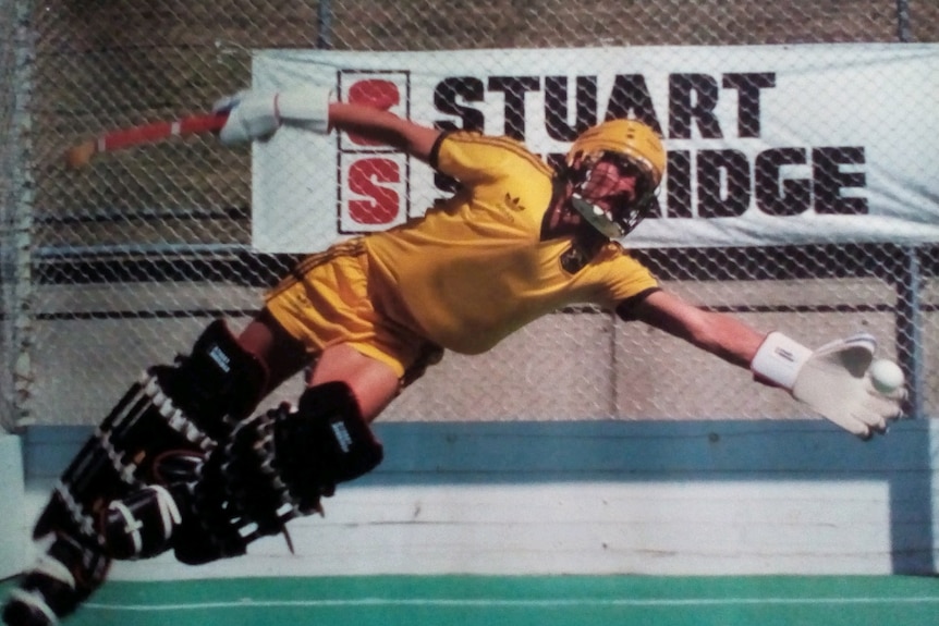 Hockey goalkeeper dives to catch a ball