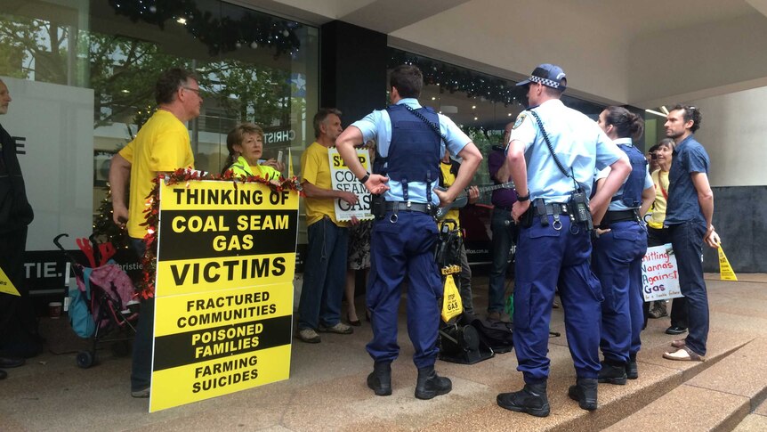 Police officers stand watch as a dozen people protest outside the Metgasco AGM in North Sydney.