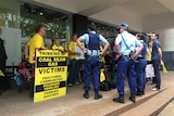 Police officers stand watch as a dozen people protest outside the Metgasco AGM in North Sydney.