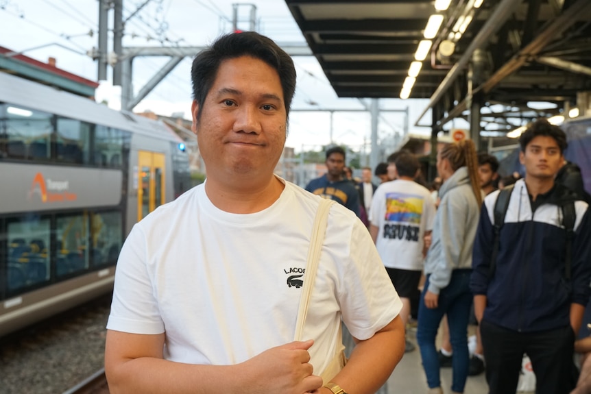 A young man in a white t-shirt at train station
