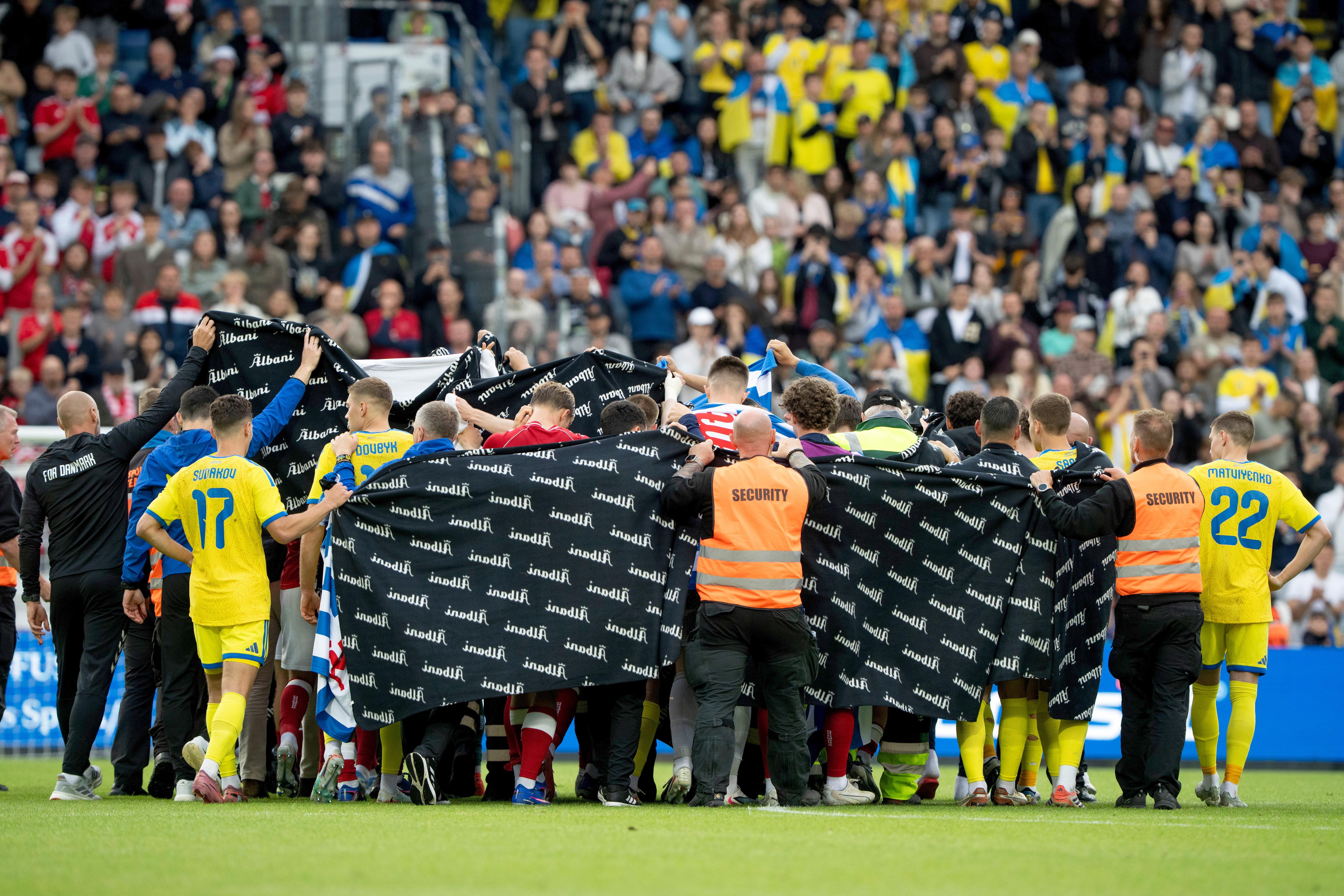 Denmark's and Ukraine's players accompany Christian Eriksen to a waiting ambulance.