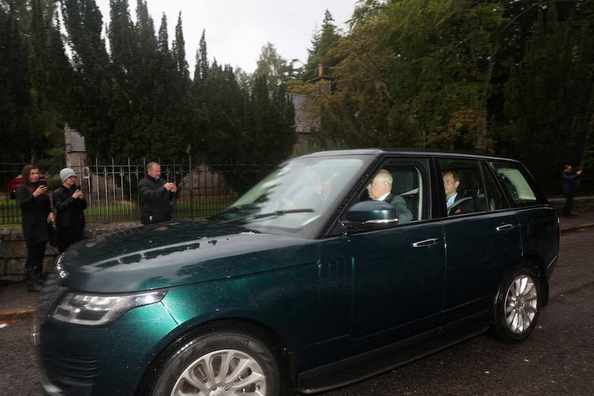 A green Range Rover arrives at palace gates with three men in the car.