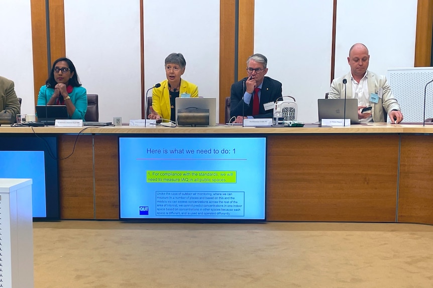 A panel of participants at the Clean Air Forum in Parliament House, with air purifiers and a CO2 monitor around the room