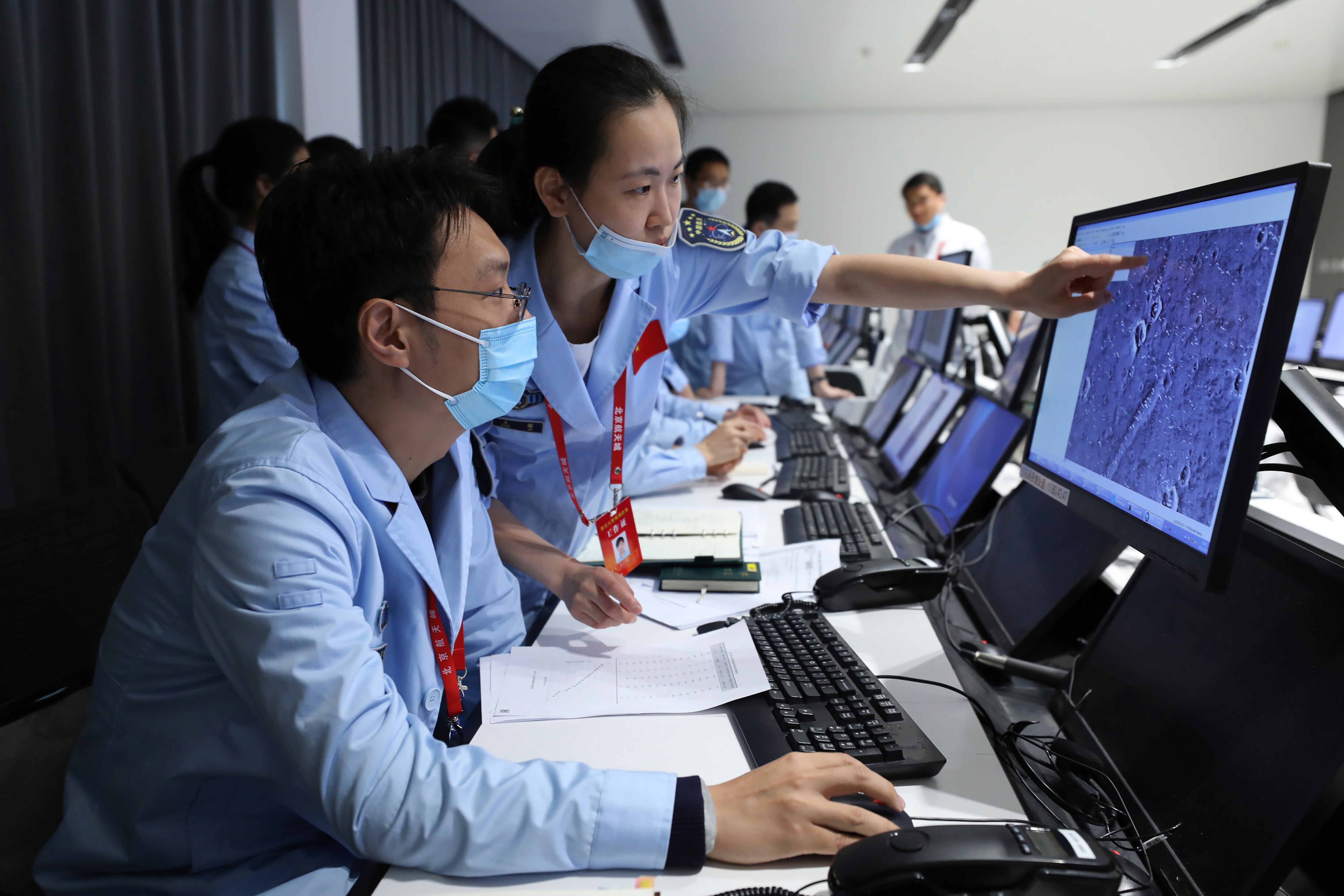 People point at computer monitors and work at the Beijing Aerospace Center.