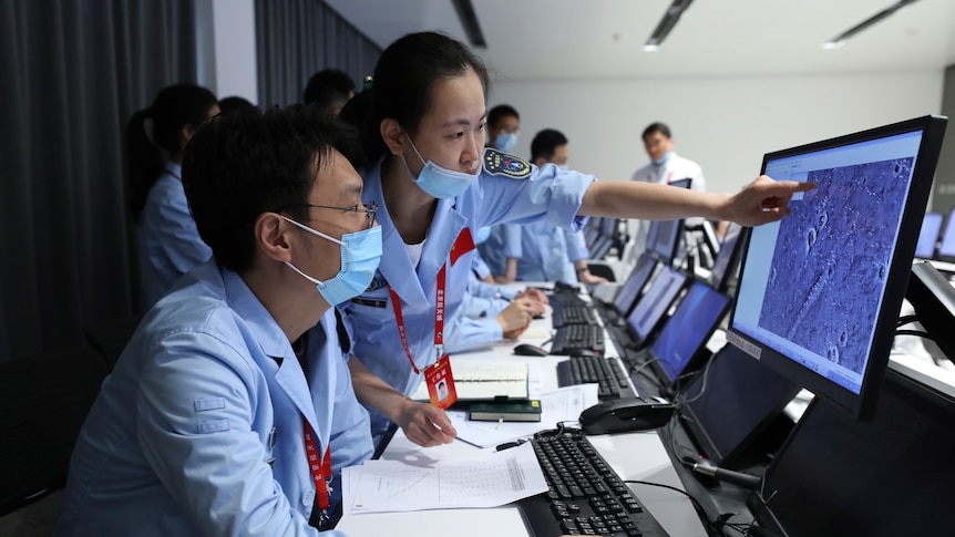 People point at computer monitors and work at the Beijing Aerospace Center.