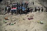 Iraqi soldiers stand next to a mass grave in Tikrit