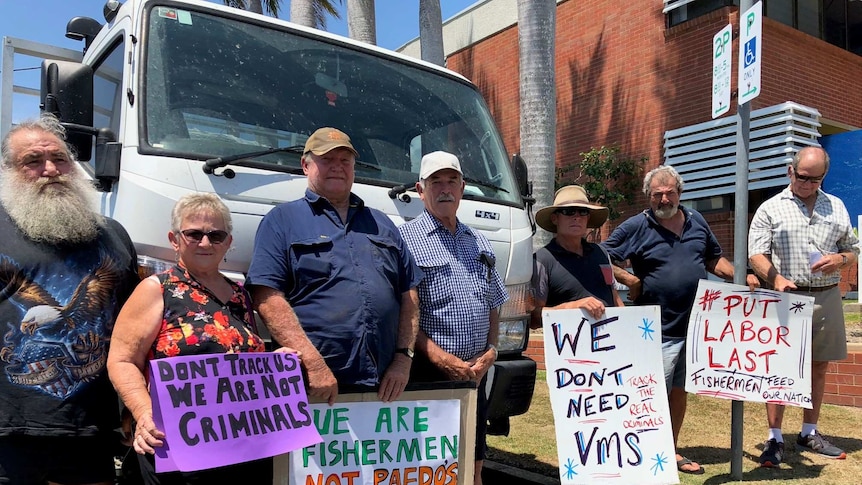 Protesters holding signs in front of a truck