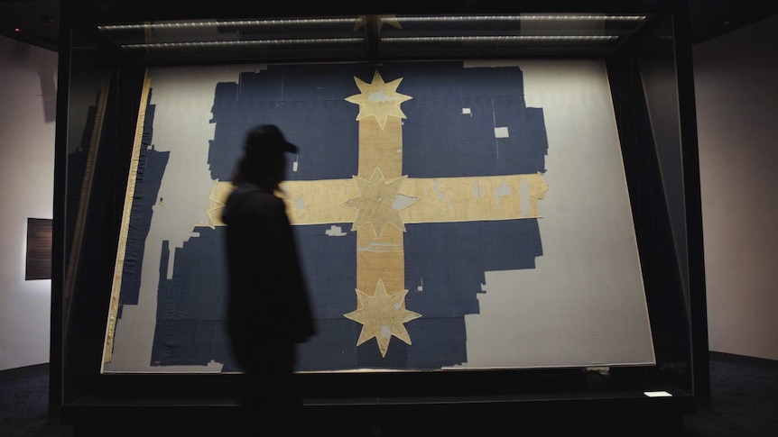 A man walks past the tattered and torn Eureka flag raised during the miner's uprising in Ballarat in 1854 mounted in a museum.