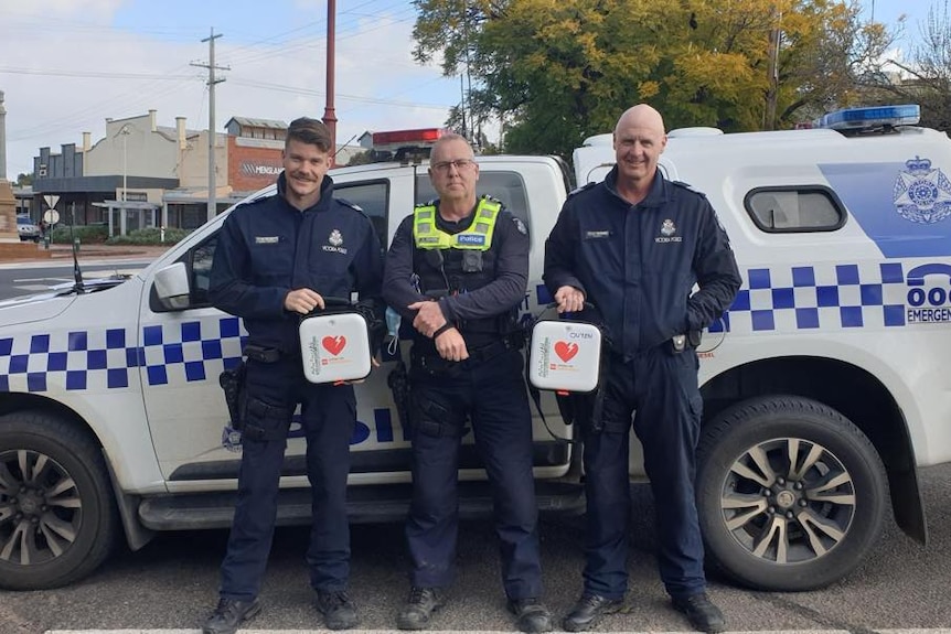 Three ;police officers with a car and defibrillators 