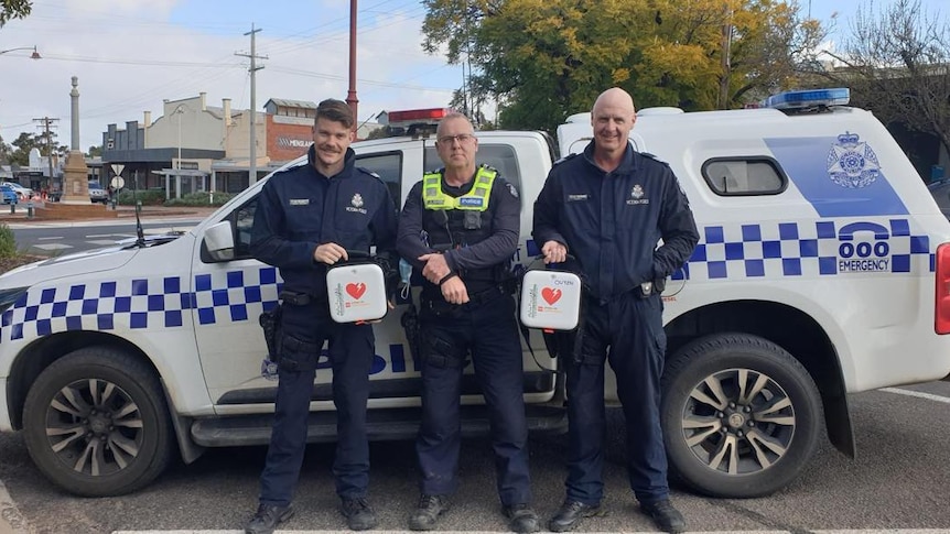 Three ;police officers with a car and defibrillators 