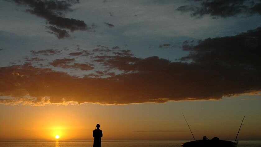 A man admires the sunset at Neds camping spot near Exmouth on the north coast of Western Australia, July 2010.