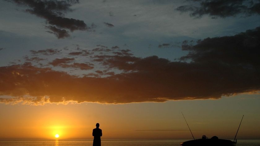 A man admires the sunset at Neds camping spot near Exmouth on the north coast of Western Australia, July 2010.