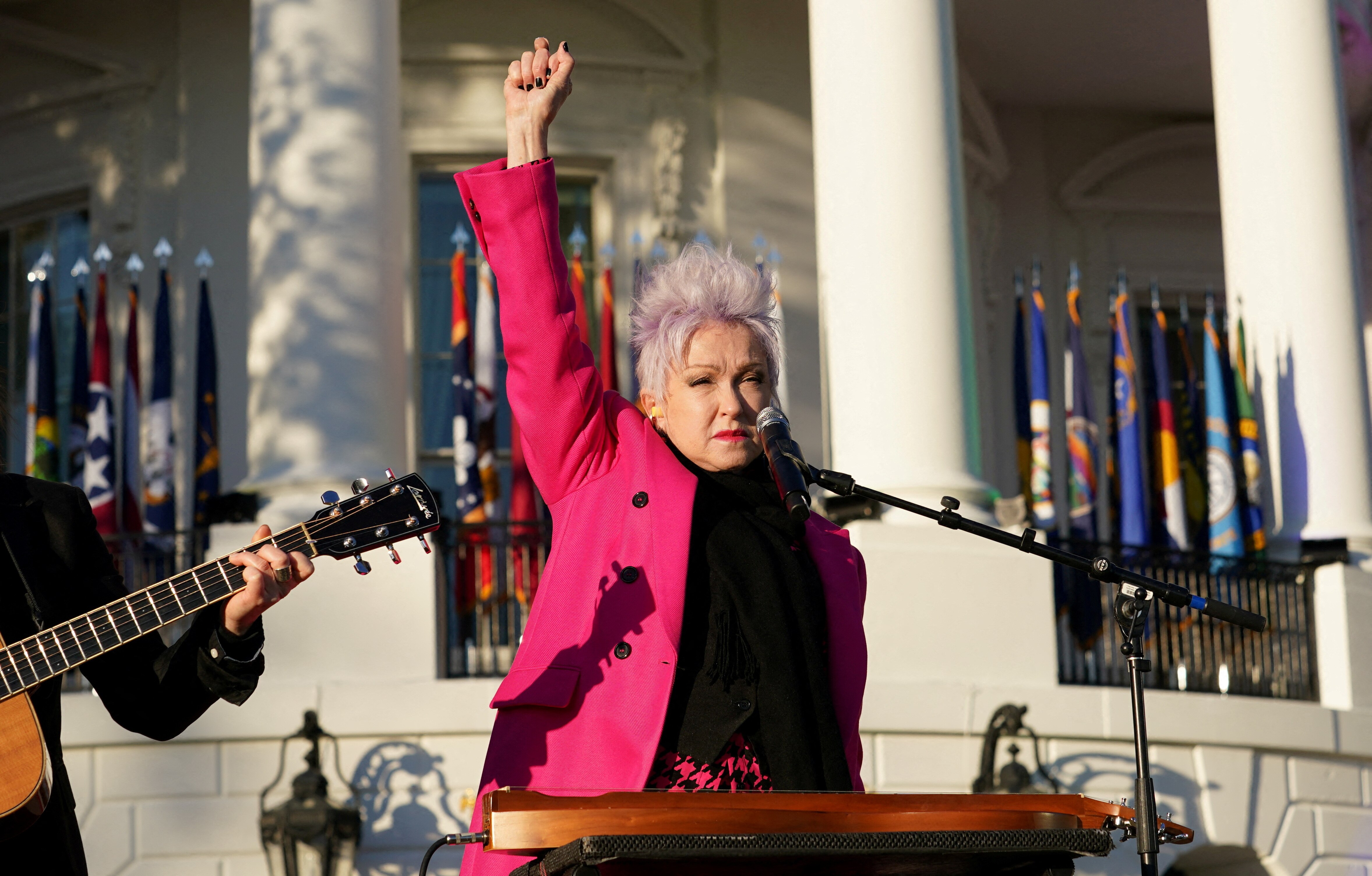 A woman in a pink coat with her arm raised