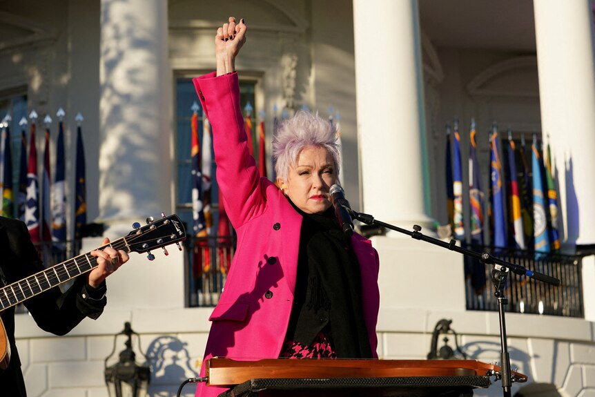 A woman in a pink coat with her arm raised