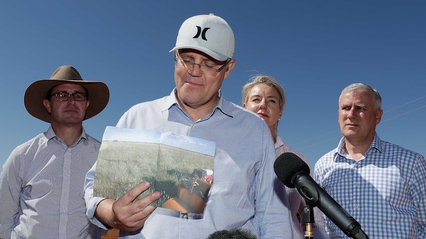 Prime Minister Scott Morrison holds up a photo of what a property used to look like before the drought.