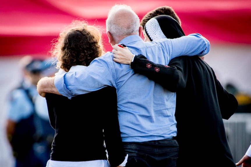 A group of people from behind with their arms around each other