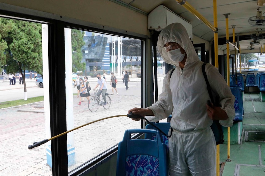 A man in a protective suit disinfects the inside of a trolley bus in Pyongyang