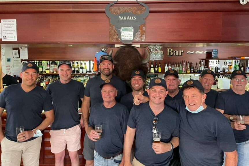 A group of 10 men stand in front of a bar 