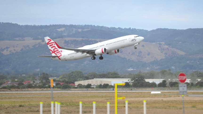 An aeroplane taking off with airport buildings behind