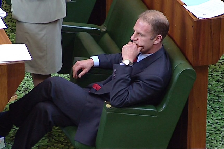 A man sits on a chair in parliament.