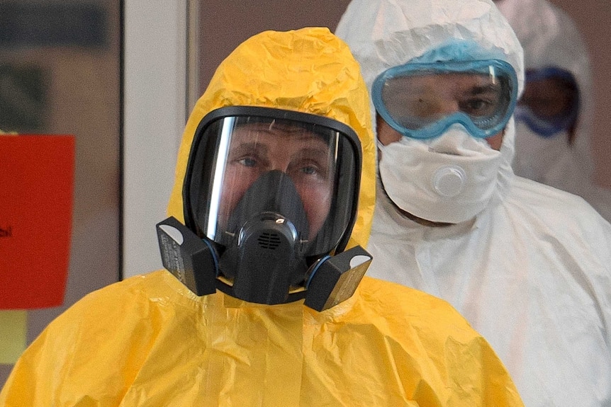 Russian President Vladimir Putin wears a protective yellow suit and full-face mask.