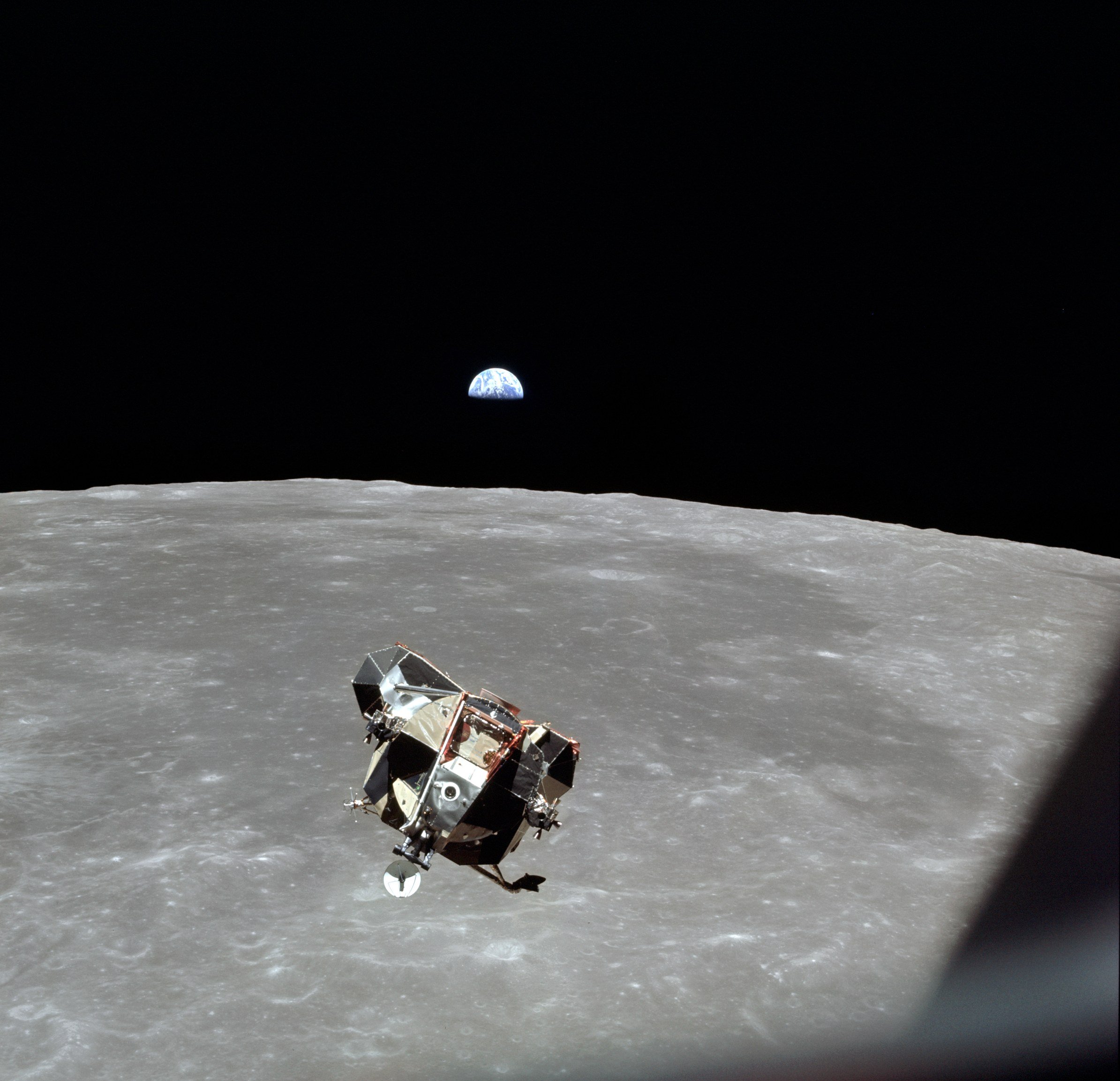 A spacecraft floating above the Moon, with the Earth in the distance.