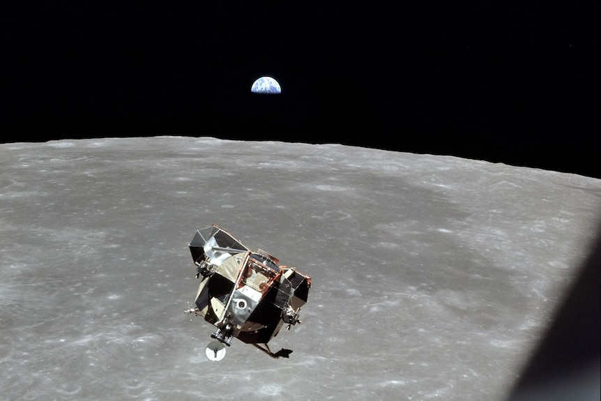 A spacecraft floating above the Moon, with the Earth in the distance.