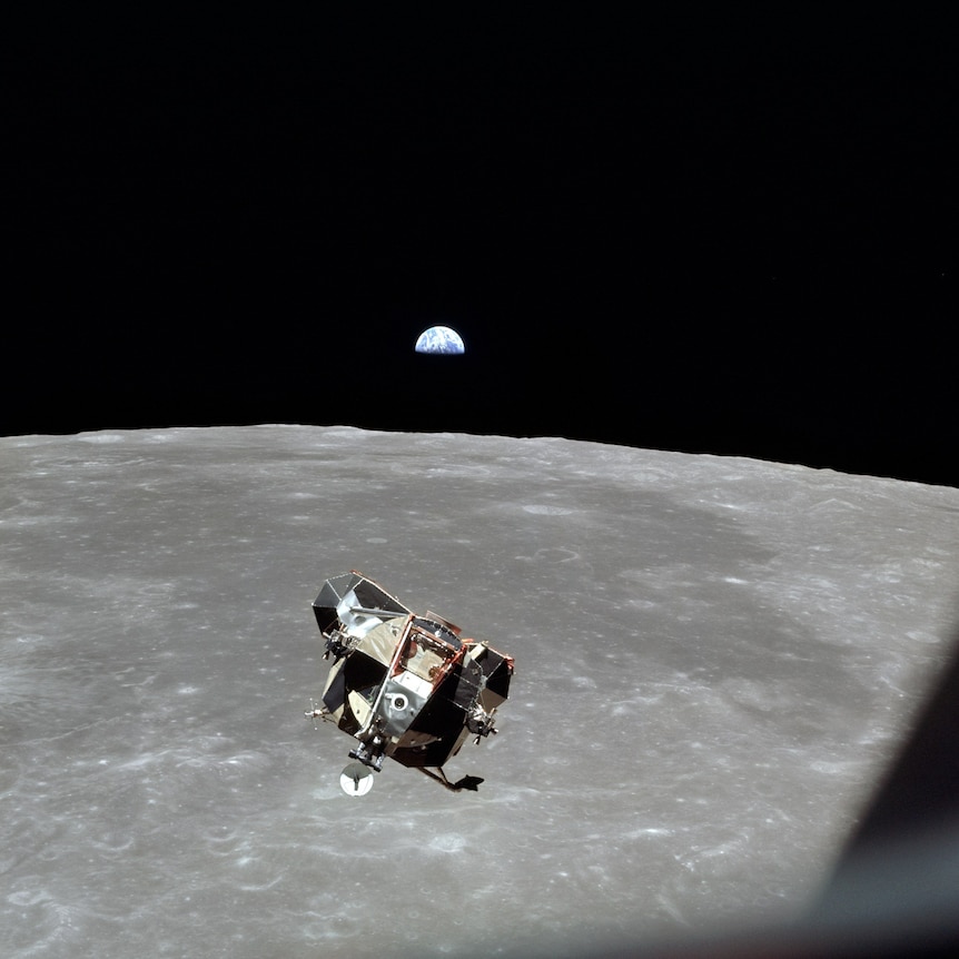 Una nave espacial flotando sobre la luna y la Tierra en la distancia.