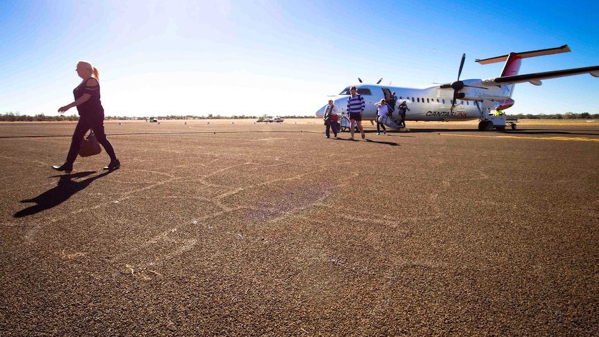 Passengers cross the tarmac after getting off a Qantaslink Dash 8 plane that's just landed at Charleville airport.