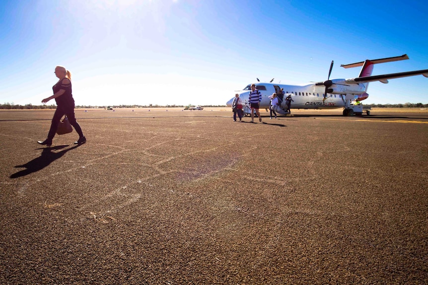 Passengers cross the tarmac after getting off a Qantaslink Dash 8 plane that's just landed at Charleville airport.