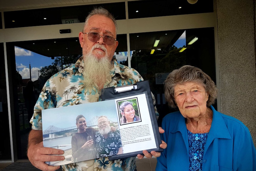 Glynn Harnell, supported by his mother, holds a picture of his daughter outside court
