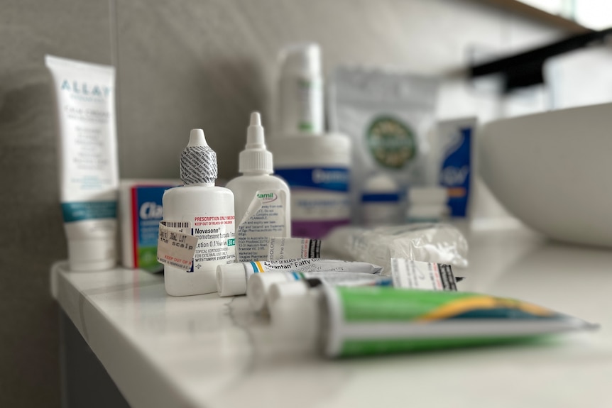 Eczema medication including creams and pill bottles on a bathroom counter