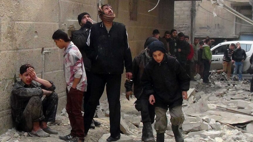 Syrian people inspect building damage following an airstrike