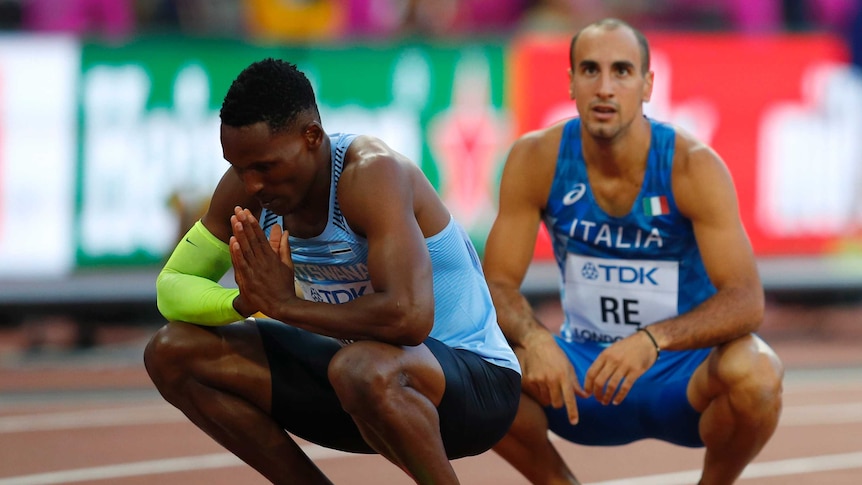 Isaac Makwala crouches on the track with his hands held together.