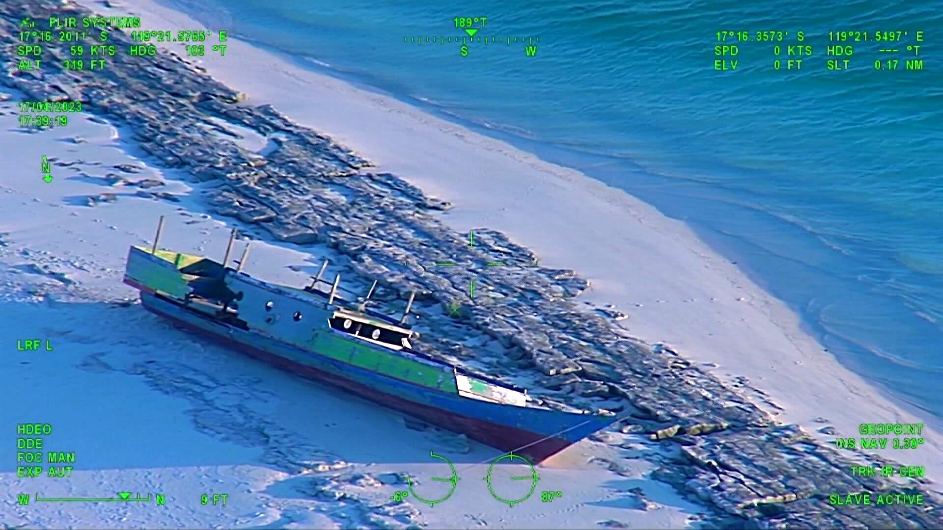 Night vision of a wooden fishing boat washed up on a beach.