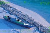 Night vision of a wooden fishing boat washed up on a beach.