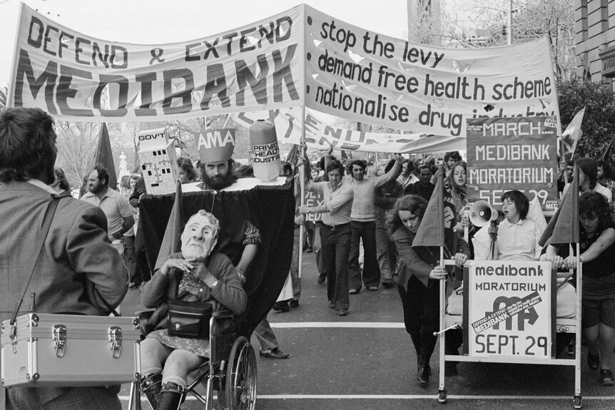 A black and white photo of a protest with signs and costumes in support of Medibank