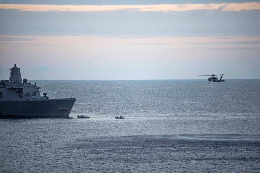 A helicopter and boats search the water.