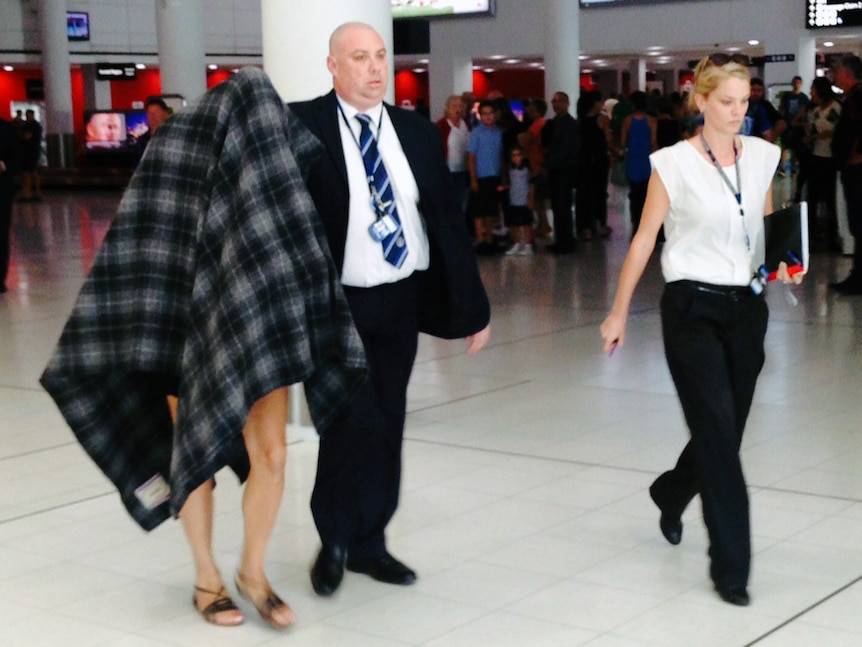 Police escort a transgender sex worker accused of transmitting HIV to another person, through Perth airport.